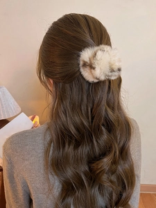 Détail de la pince à cheveux en peluche léopard sur une coiffure d'hiver pour femmes