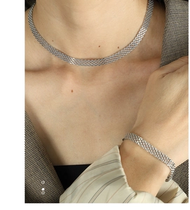 Detailed view of silver mesh woven necklace and bracelet set worn with a formal suit