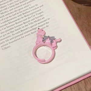 Detail of pink puppy ring with pearl necklace and zircon bow on book background