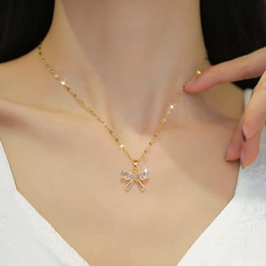 Elegant gold titanium necklace with a crystal bow pendant on a model's collarbone