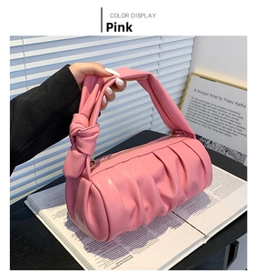 Detail of pink ruched cloud bag showing the knotted handle and gold metal zipper closure