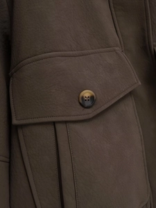 Detailed macro view of leather texture and button on brown faux leather jacket