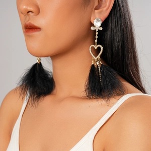 Detail of heart rhinestone earrings with black feather fringe tassel on model