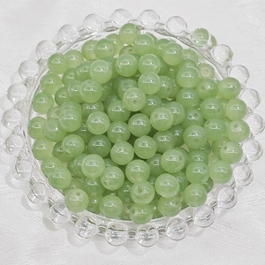 Close-up of pale green round glass beads for DIY jewelry making in a glass tray