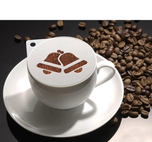 Detail of plastic coffee stencil with bell design on a ceramic cup with coffee beans