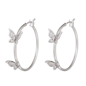 Détail de boucles d'oreilles créoles argentées avec papillons sertis de zircons