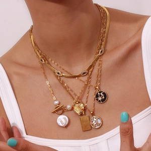 Detail of layered gold necklaces with baroque pearl and evil eye charms on a model