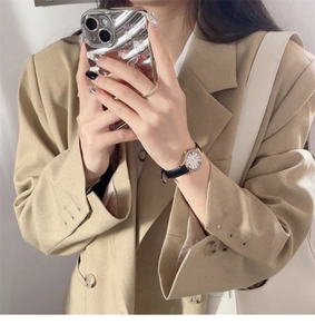Elegant gold watch with a shell dial and black leather strap on a woman's wrist