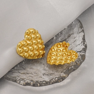 Macro detail of gold-plated heart earrings with unique 3D bubble texture and secure backings