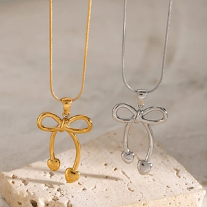 Detail of bow-shaped pendants with heart accents in gold and silver finishes