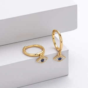 Macro detail of gold S925 silver Evil Eye hoop earrings with blue and white stones