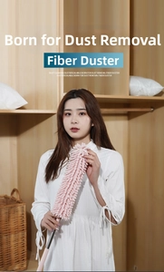 Pink chenille duster with telescopic pole cleaning dust from a wooden wardrobe corner