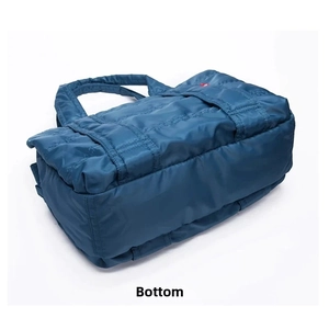 Detailed bottom view of navy quilted nylon travel bag with reinforced square stitching