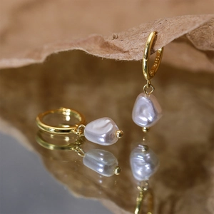 Macro shot of S925 sterling silver earring with baroque pearl drop and elegant gold clasp