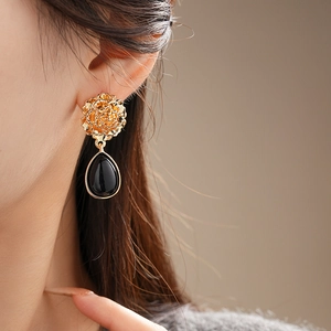 Close-up of vintage flower earrings with black teardrop drops worn on a model