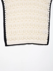 Détail du tricot au crochet avec liseré noir contrasté et bordure festonnée élégante