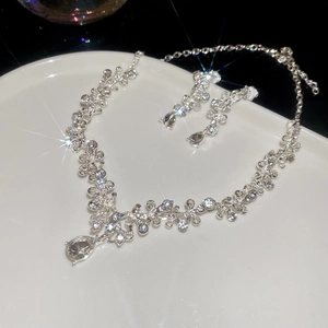 Sparkling silver necklace and earrings set with crystal droplets and hollow floral charms