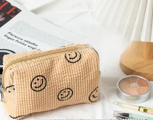 Detail of beige corduroy storage bag with black smiley faces and metal zipper close