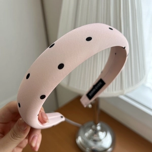 Close-up of pink polka dot padded headband with hand-made label and satin fabric detail