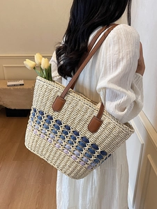 Handwoven straw tote bag with blue floral pattern and brown leather straps for summer beach