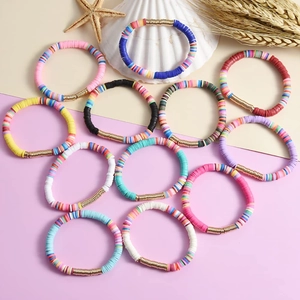 Close-up of colorful clay bead friendship bracelets with starfish and shells on sand