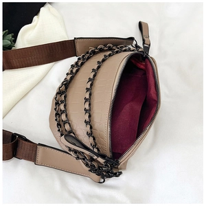 Detail view of beige crocodile texture waist bag with decorative black metal chains