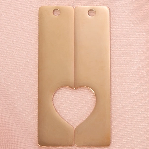 Close-up of two rose gold rectangular tags with heart-shaped cutout on pink fabric