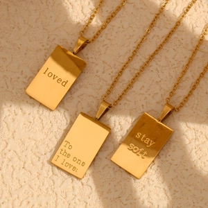Macro shot of 18K gold plated rectangular pendant necklaces with engraved inspirational words