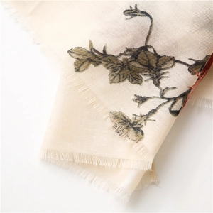 Detailed close-up of retro floral prints and frayed edges on a beige linen shawl