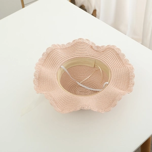 Detail of pink straw hat showing scalloped edge and interior white elastic chin strap