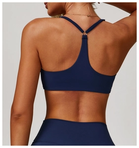 Detail of dark blue sports bra featuring cross-back straps and a metal ring connector