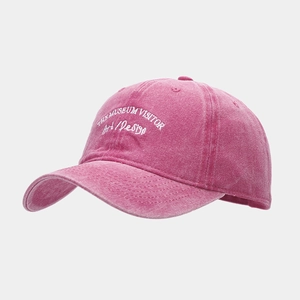 Close-up of white letter embroidery and stitching on a rose red washed cotton baseball cap