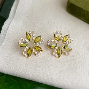 Detailed macro view of olive green flower stud earrings with shimmering zircons