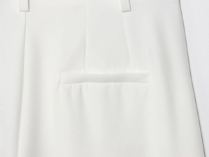 Détail d'un pantalon blanc avec poche passepoilée et pinces pour une coupe ajustée