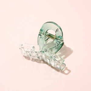 Detail shot of a transparent green and clear acetate hair claw with a visible metal spring