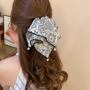 Detailed back view of a woman wearing a cream bow hair claw clip with pearl pendants