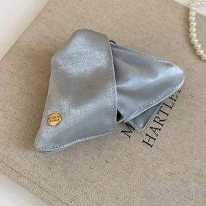Detail of silver grey satin hair claw featuring a gold button with Believe In Yourself text