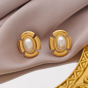 Detailed macro view of vintage gold plated earrings with a central pearl on silk