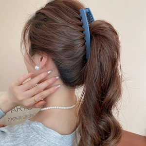 Vue détaillée d'une pince à cheveux mate bleue fixant une queue de cheval brune