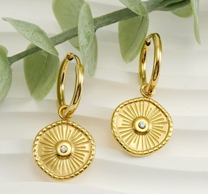 Macro shot of 18K gold plated compass earrings with sunburst pattern and central crystal