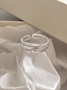 Detail of silver double-layered fish ring with small diamond in a beige gift box
