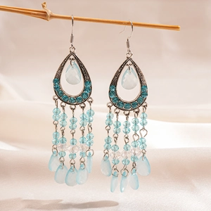 Detail of bohemian teardrop earrings with blue beads on silk background fabric