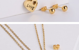 Detail of gold titanium steel heart pendant with LOVE engraving and round ball earrings