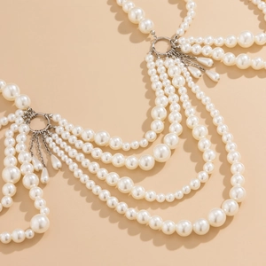 Detail view of multi-layered pearl body chain with intricate white beads and metal fringe