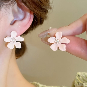 Close-up of pink flower stud earring with central pearl and golden beads detail