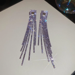 Macro shot of silver tassel drop earrings featuring sparkling rhinestones and starburst effect