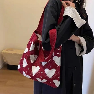 Close-up of red knitted tote bag with white heart pattern on model shoulder