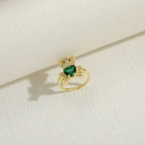 Macro shot of 14K gold bear ring holding a green heart-shaped zircon gemstone