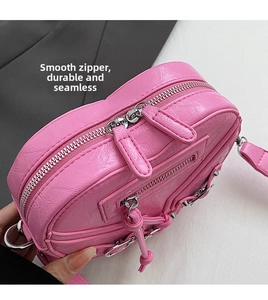 Détail du sac cœur rose montrant les doubles fermetures éclair et les anneaux métalliques