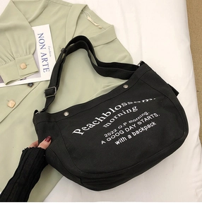 Détail du sac cabas en toile noire avec lettrage blanc et bandoulière réglable